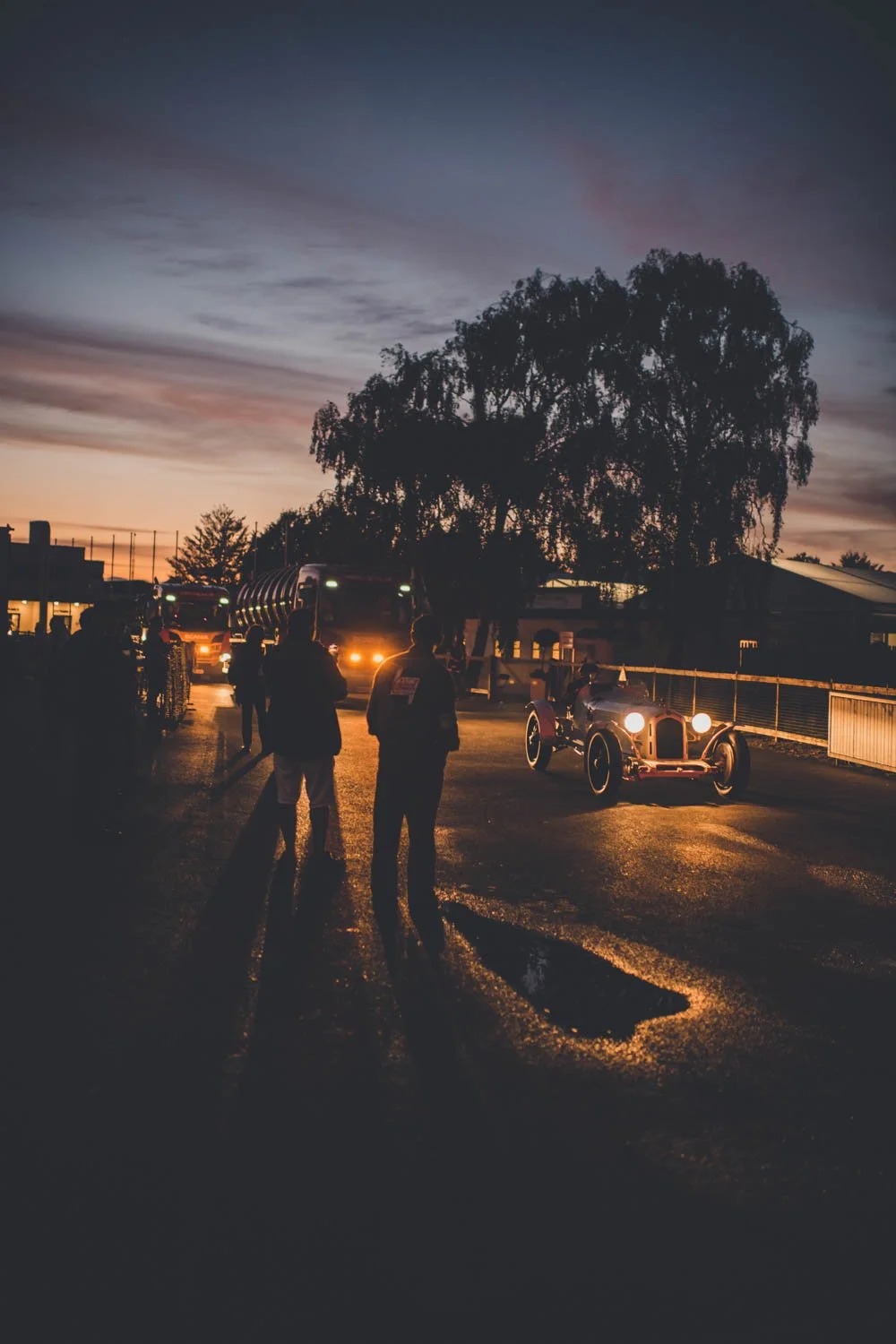 A vintage rally car arriving at dusk